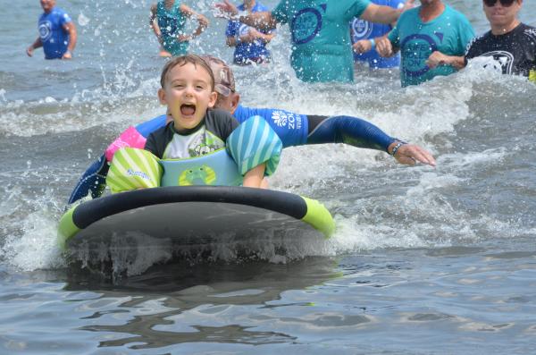 A child in the ocean surfing with others.